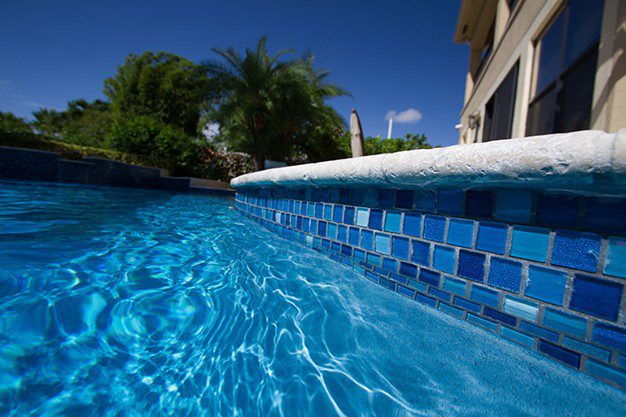 A pool with blue tiles and a white ledge